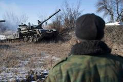 A man watches a tank of the separatist self-proclaimed Donetsk People's Republic Army manoeuvre near a checkpoint on the road from Vuhlehirsk to Debaltseve