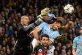 Barcelona's goalkeeper Valdes punches the ball past Barcelona's Fabregas and Manchester City's Kompany and Demichelis during their Champions League round of 16 first leg soccer match against Barcelona