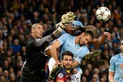 Barcelona's goalkeeper Valdes punches the ball past Barcelona's Fabregas and Manchester City's Kompany and Demichelis during their Champions League round of 16 first leg soccer match against Barcelona