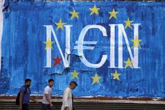 Řecko Men walk by fresh anti-EU graffiti in Athens, Greece
