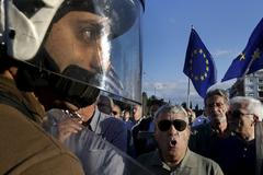 Policista mezi demonstranty v Aténách. Do ulic vyšli v pondělí zastánci i odpůrci eurozóny.