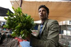 Jemenský překupník prodává lístky kátu na tržnici v Saná.