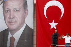 Turecký premiér Davutoglu (vpravo) na pódiu s obřím portrétem prezidenta Erdogana.
