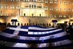 Demonstranti nesou řeckou vlajku