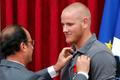 French President Francois Hollande awards US Airman First Class Spencer Stone with the Legion d'Honneur medal as US National Guardsman Alek Skarlatos applauds during a ceremony at the Elysee Palace in