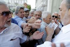 Řecko Pensioners are given priority tickets as they wait to receive part of their pensions at a National Bank branch in Athens
