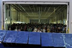 Syrští uprchlíci se chystají vyjít na pevninu v řeckém přístavu Pireus.