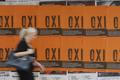 A woman makes her way past posters that show the word 'No' in Greek in Athens