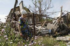 Ukrajinka před svým zničeným domem.