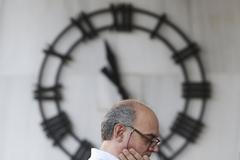 Muž čeká na výběr za bankomatu v centru Atén.