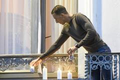 Salahův bratr Mohamed Abdeslam zapaluje na balkonu svého bytu v bruselské čtvrti Molenbeek svíčky za oběti pařížských útoků.