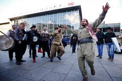 Uprchlíci tančí během karnevalu před budovou hlavního nádraží v Kolíně nad Rýnem.