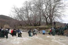 Běženci přecházejí řeku západně od Idomeni.