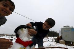 Foto: Dětem z Rakky se sníh líbí. Uprchlíci staví sněhuláky v Libanonu, bez bund a v pantoflích