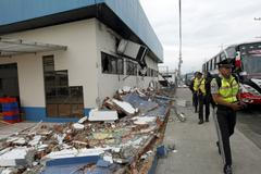 Police officers walk next to debris after an earthquake struck off Ecuador's Pacific coast, at Tarqui neighborhood in Manta
