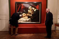 Visitors looks at a painting entitled "Judith Beheading Holofernes" during its presentation in Paris
