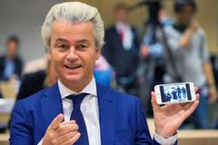 Dutch far-right Party for Freedom leader Geert Wilders shows the picture of the photographers he took with his cell phone prior to his trial in the courtroom in the courthouse in Schiphol