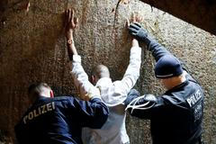 Němečtí policisté prohledávají zadrženého muže.