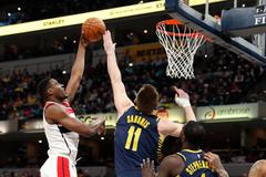 Ian Mahinmi z Washingtonu (vlevo) střílí přes blok Domantase Sabonise na koš Indiany