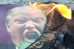 Zapálená fotografie Trumpa na demonstraci proti náletům v Simferopolu na Krymu.