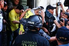 Od filipínského soudu odvádějí jednoho z policistů obviněných ze zabití 17letého mladíka.