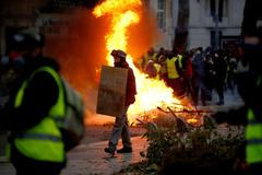Protestující prochází kolem hořící barikády během demonstrace hnutí žlutých vest v Nantes.