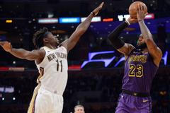 NBA 2018/19, LA Lakers - New Orleans: Hostující Jrue Holiday se snaží zablokovat střelu LeBrona Jamese.