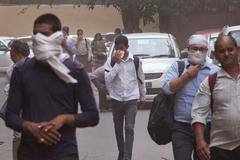 Lidé v Novém Dillí nosí kvůli písečné bouři roušky.