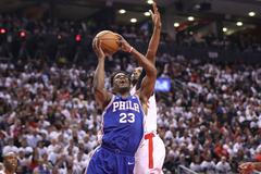Jimmy Butler z Philadelphie se v utkání play off NBA pokouší prosadit přes Normana Powella z Toronta