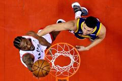 Kawhi Leonard (vlevo) z Toronta skóruje v pátém utkání finále NBA do koše Golden State