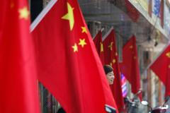A woman stands amid Chinese national flags ahead of the 70th founding anniversary of People's Republic of China in Beijing