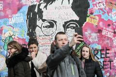 Lennonova zeď po třech měsících od malování - turisté, graffiti