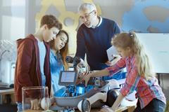 Učitel a jeho žáci pracují na programovatelném robotu s LED osvětlením pro projekt School Science Class