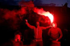 Fanoušci Liverpoolu oslavují před stadionem Anfield Road na dálku titul v Premier League