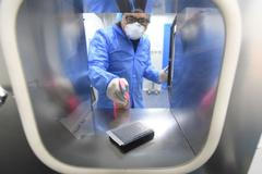 Muž v ochranném oděvu zkoumá vzorky v nemocnici ve Wu-chanu.