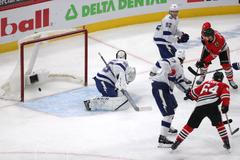 Útočník Chicaga Dominik Kubalík (8) skóruje do sítě gólmana Tampy Bay Curtise McElhinneyho (35).