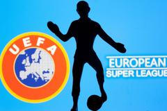 A metal figure of a football player with a ball is seen in front of the words "European Super League" and the UEFA logo in this illustration