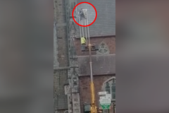 Muž na dvou žebřících a jeřábu opravoval střechu kostela