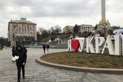 Muž kráčí v centru Kyjeva se dvěma bílými holubicemi. Ale na mír to zatím nevypadá.