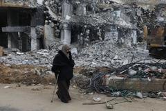 Žena v Palestině prochází kolem trosek budovy, kterou v Gaze zasáhl izraelský nálet.