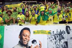 Brazilští fanoušci s transparentem se snímky Pelého před osmifinále MS 2022 Brazílie - Jižní Korea