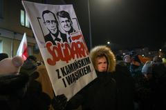 Protestující drží ceduli s podobiznami zadržených bývalých poslanců Mariusze Kaminského a Macieje Wasika poblíž policejní stanice Grochow ve Varšavě v Polsku dne 9. ledna 2023.