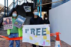 Prodemokratický aktivista drží před úřadem čínské vlády v Hongkongu transparenty s fotografií čínské občanské novinářky Čang Čan, 28. prosince 2020.