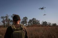 Specialista ovládá odminovávací dron nad polem u města Derhači na severovýchodě Ukrajiny.