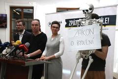 Pirátští poslanci Ivan Bartoš, Olga Richterová a Jakub Michálek na tiskové konferenci v dubnu 2025, na které chtěli s pomocí kostry ilustrovat "vykostění" některých schválených zákonů.