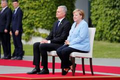 Po opakovaných záchvatech třesu seděla Angela Merkelová při vojenské přehlídce na židli