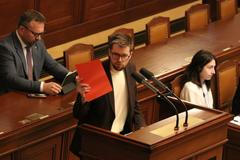 Předseda pirátských poslanců Jakub Michálek ve chvíli, kdy "udělil" ministrovi spravedlnosti Pavlu Blažkovi červenou kartu.