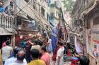 Residents stand in an alley after vacating their house next to a fallen scaffolding following an earthquake in Dhaka