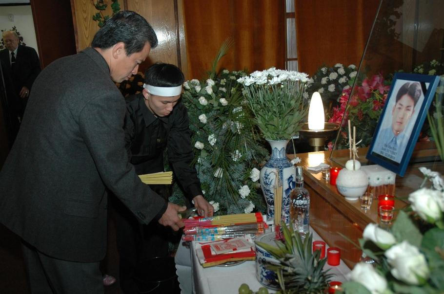 Pozůstalí zapalují vonné tyčinky u rakve vietnamského barmana Dao Van Tinha během pohřbu v chomutovské obřadní síni.