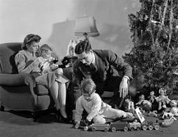 1930s 1940s FAMILY AROUND CHRISTMAS TREE BOY PLAYING WITH TRAIN DAD HELPING MOM AND GIRL IN CHAIR